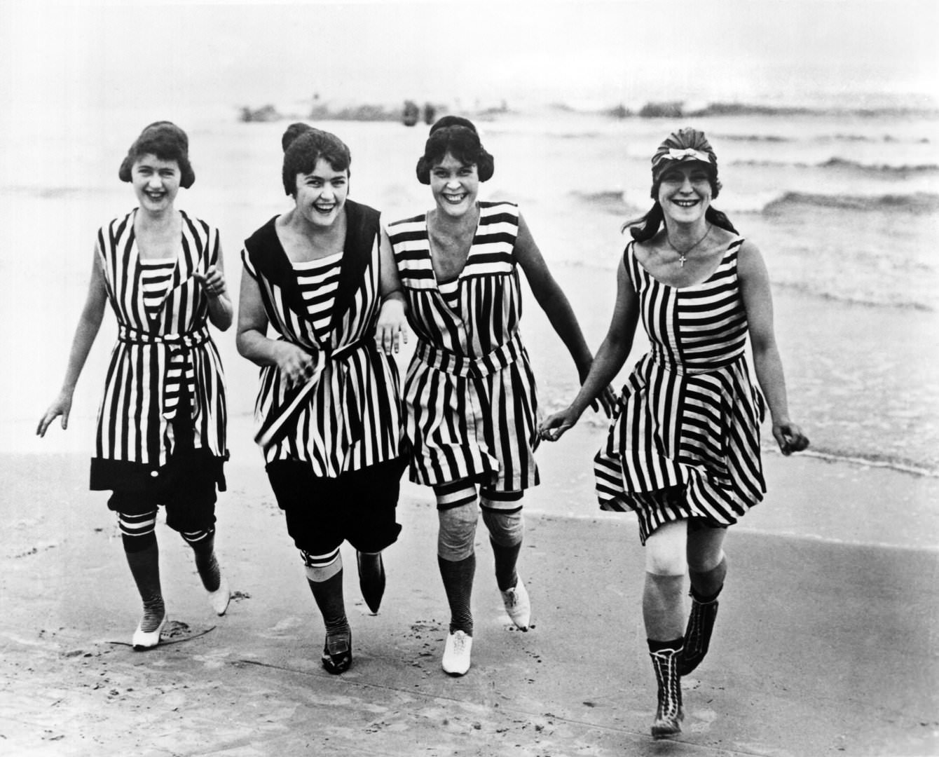 Four young women in matching beach wear run out of the surf, Los Angeles, 1910