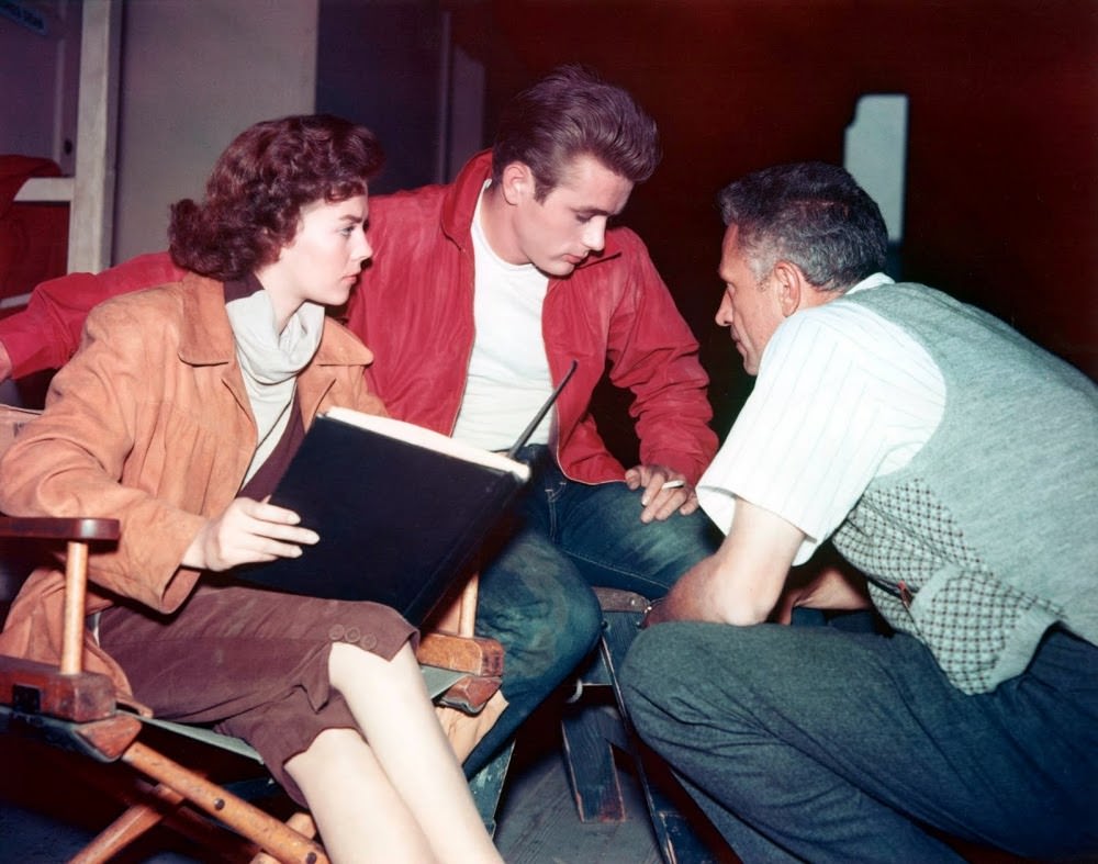 Natalie Wood and James Dean hear from director Nicholas Ray in a quiet moment between filming, 1955