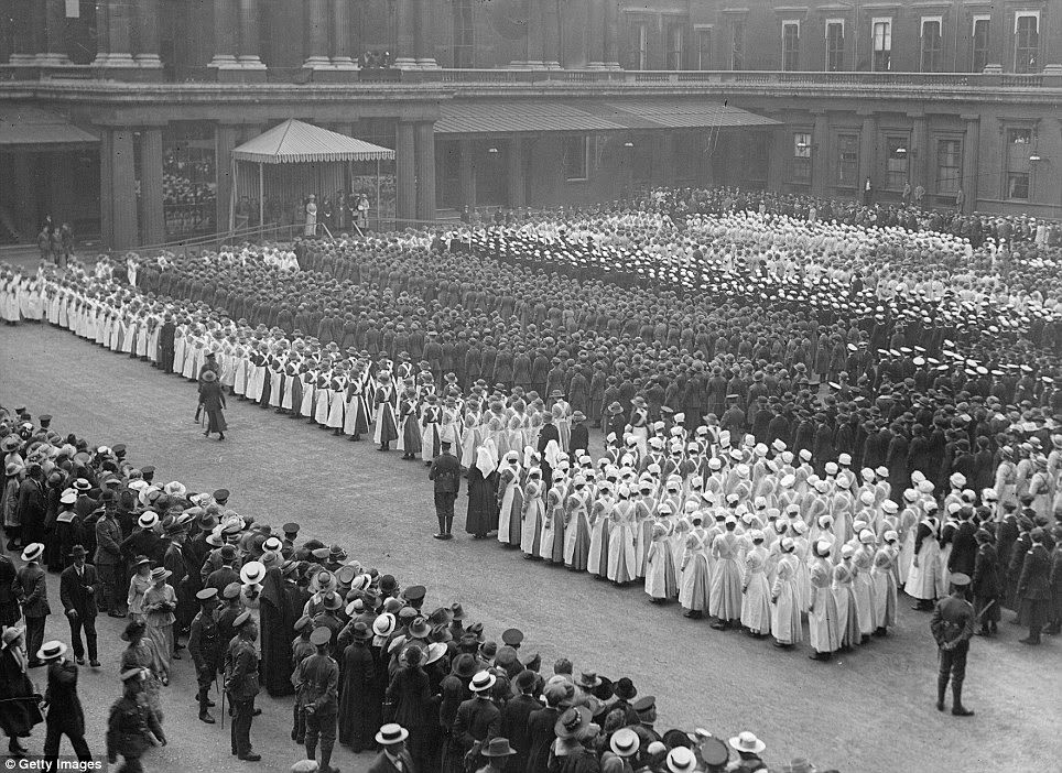 Women war workers, including the distinctively white-capped and aproned VAD nurses, parade outside Buckingham Palace in 1918.