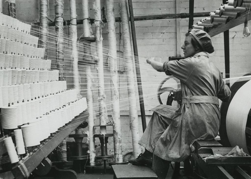 British woman winding cotton from spools on to rollers at lace factory in Nottingham