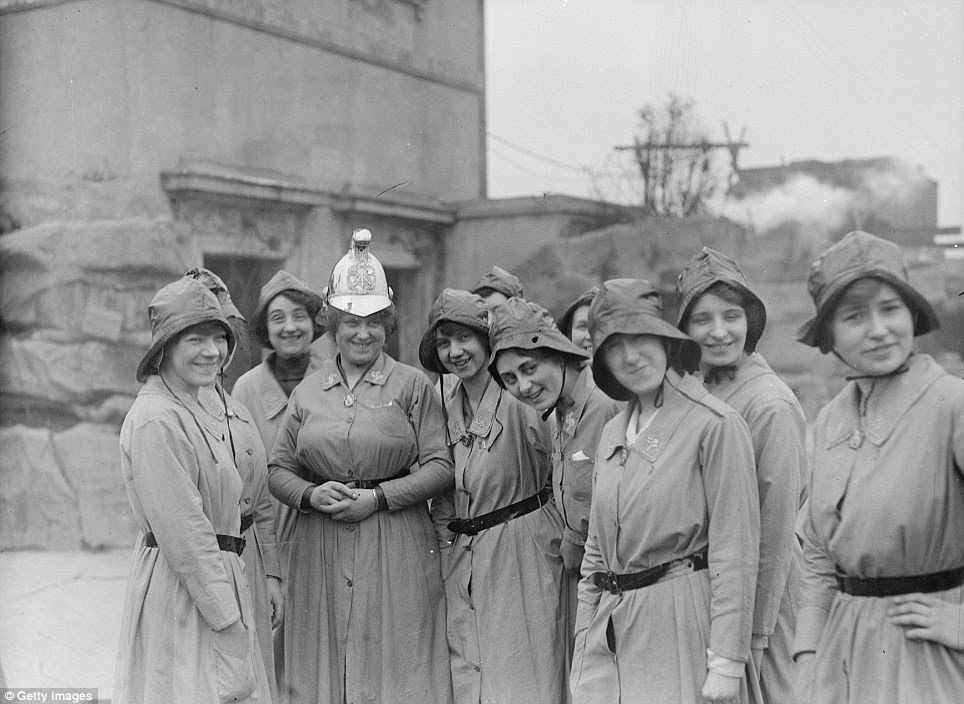 Members of the Women’s Fire Brigade with their Chief Officer photographed in their uniforms beside an extinguished fire in March 1916.