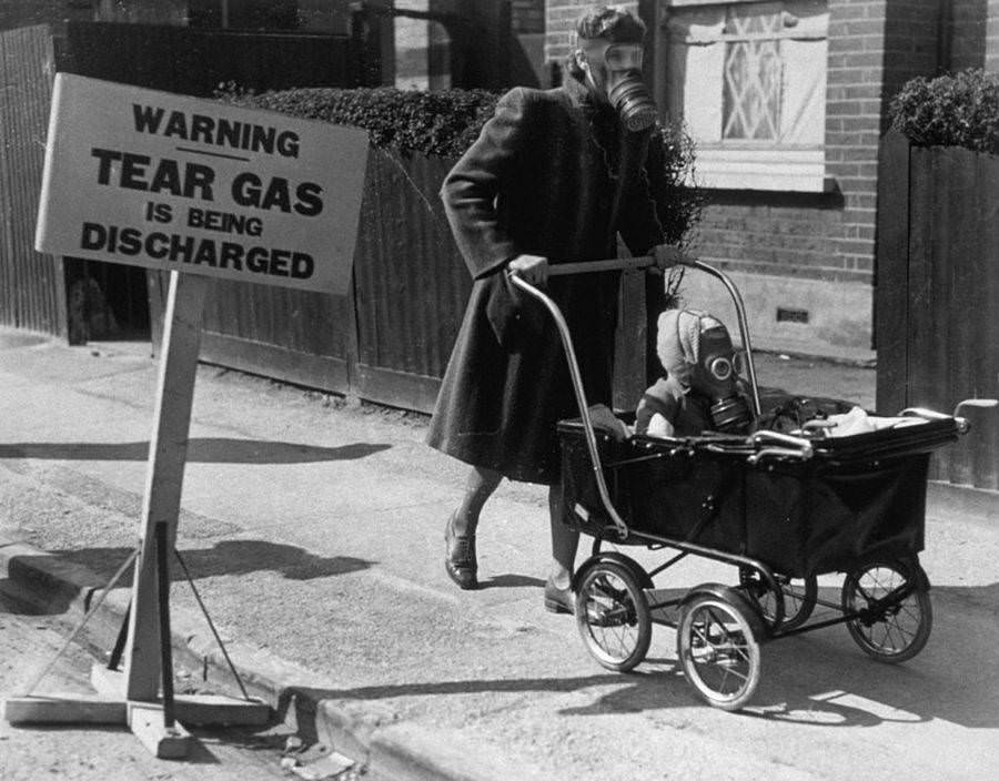 A mother and child wear gas masks during a tear gas exercise in Kingston-On-Thames, England, 1941.