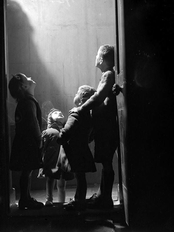 A group of London children inspect bomb damage outside their front door, 1944.