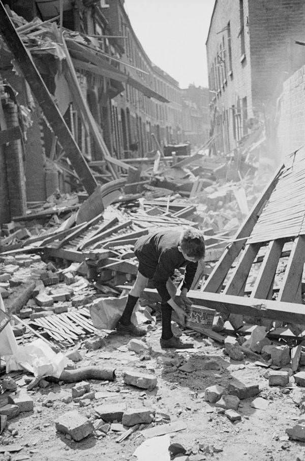 A boy retrieves an item from a rubble-strewn street after German bombing raids in the first month of the Blitz in England, 1940.