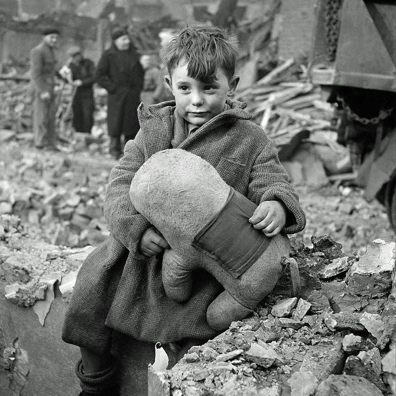 An abandoned boy holds a stuffed toy animal amid ruins following a German aerial bombing of London, 1940.