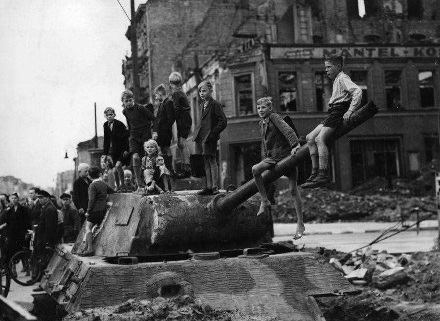 Children play on the bomb sites and wrecked tanks in Berlin in the aftermath of the fighting there. 1945.
