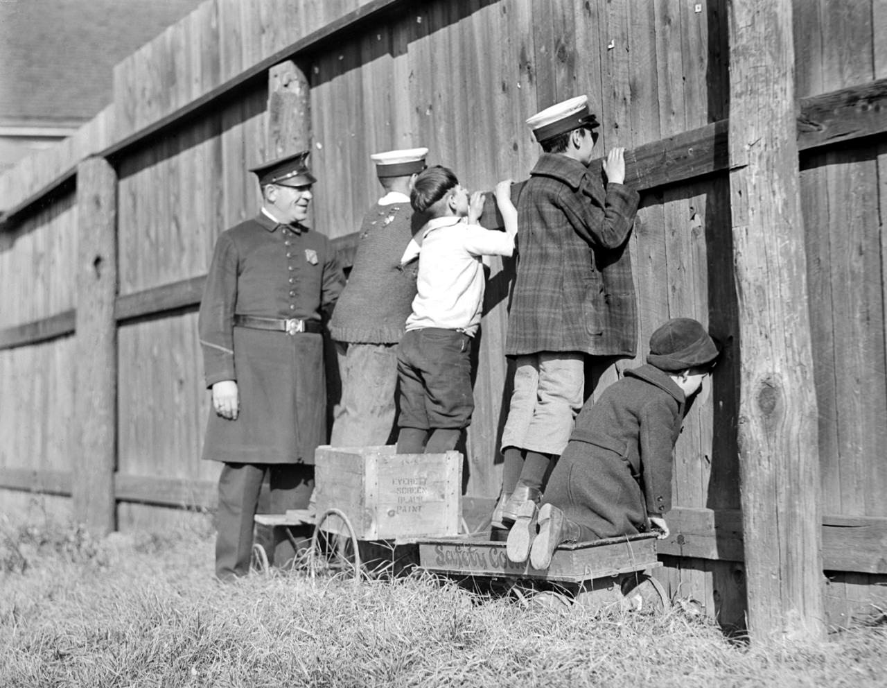 Cop joins baseball peekers at the fence in Massachusetts, 1930