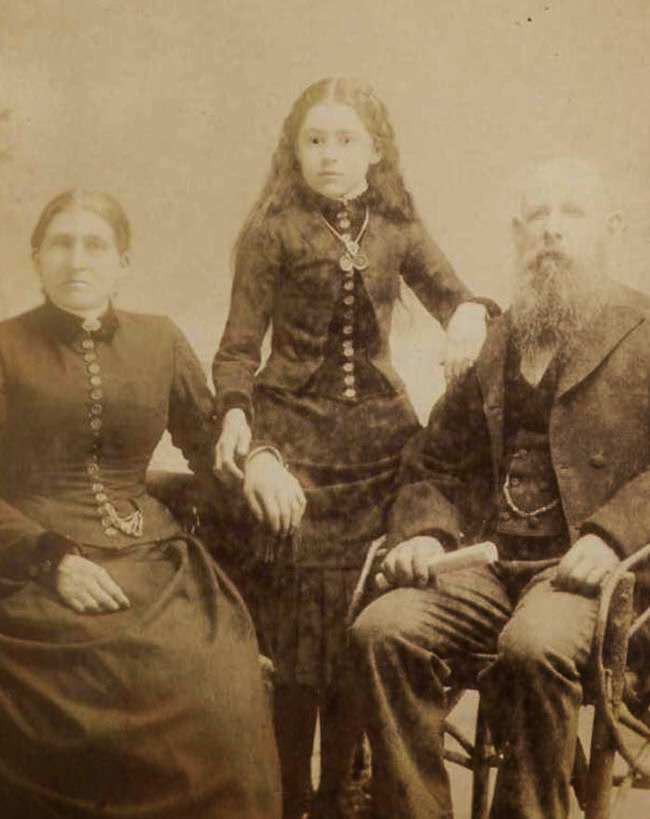 The girl standing in the middle is the deceased.The photographer attempted to make her look more alive by drawing on her pupils.