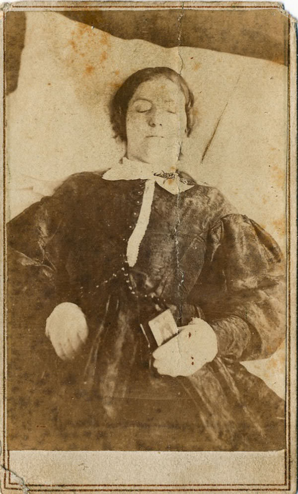 Deceased young woman is holding a small bible or testament.