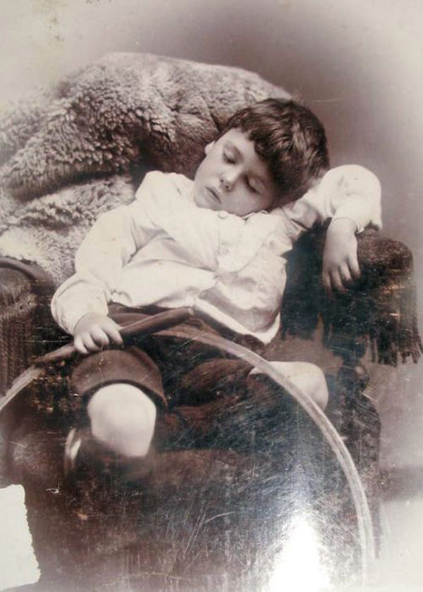 Deceased boy photographed with what was likely his favorite toy, a hoop and stick.