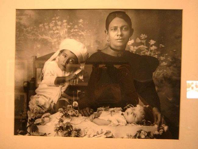 Mother and older sibling posing over a deceased infant.