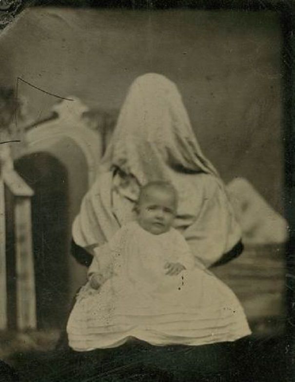 A mother covers her face while holding her dead baby.