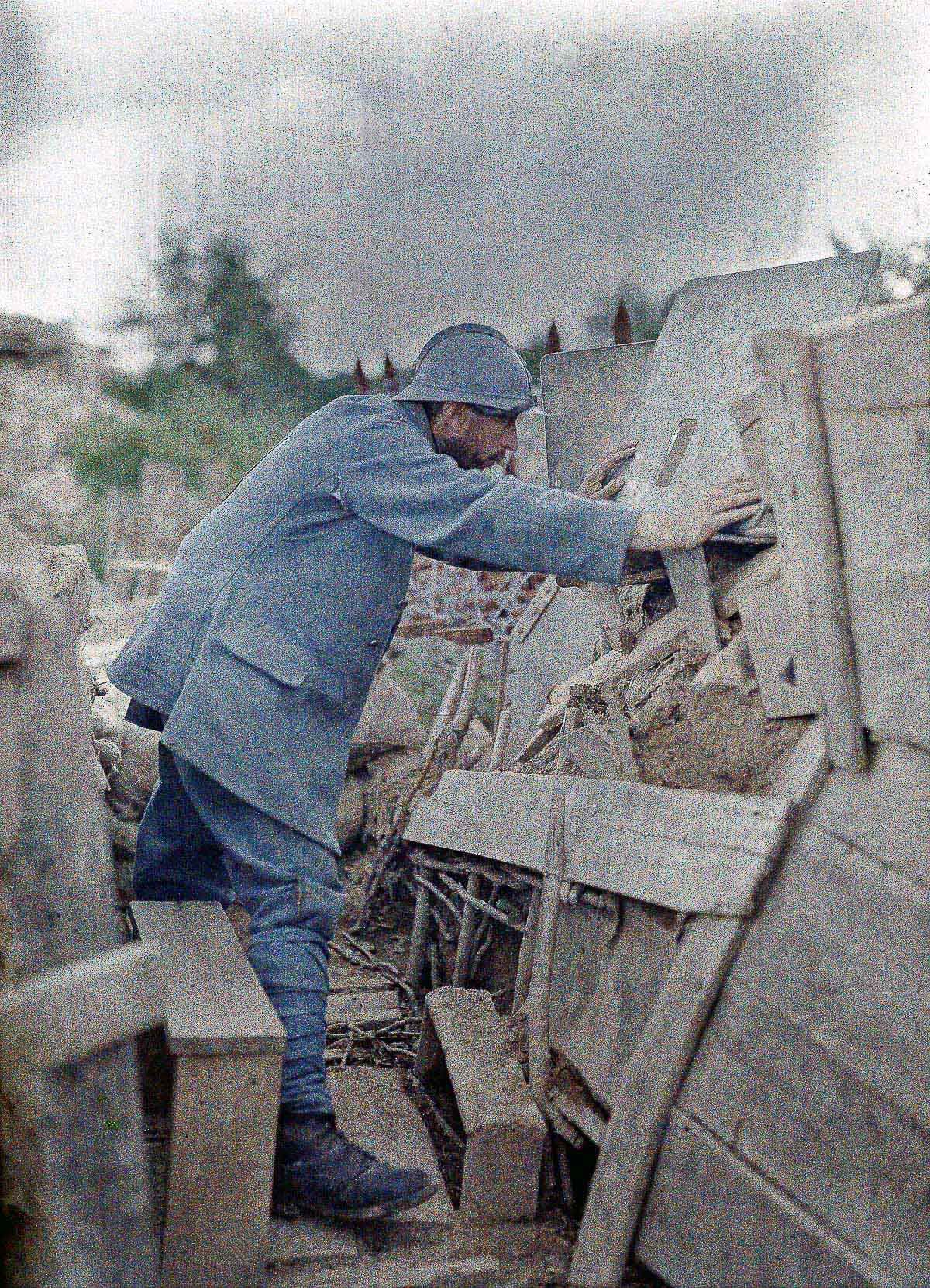 A French soldier peers out from a position on the Western Front in Alsace., 1917