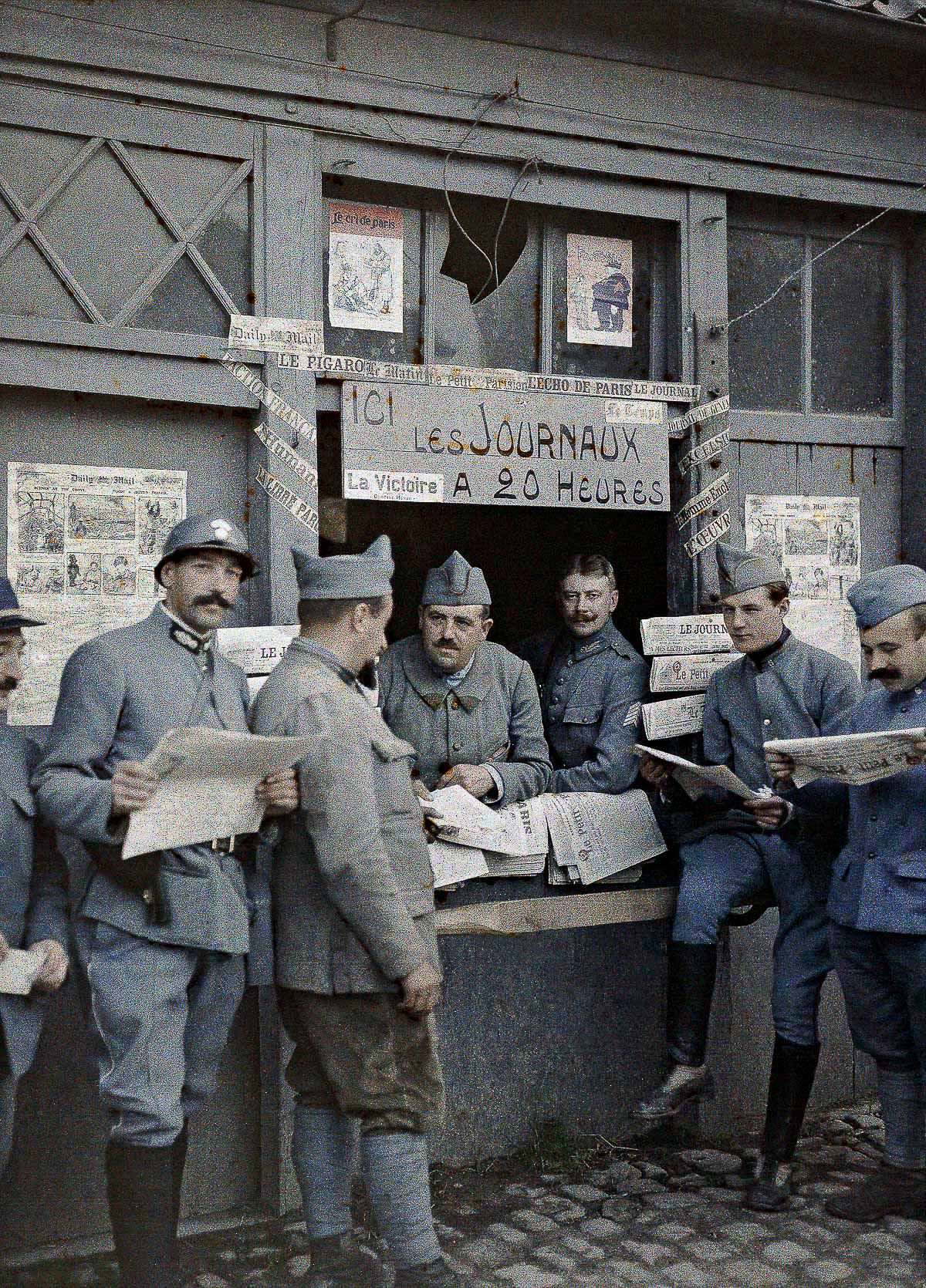French soldiers read newspapers at a kiosk in Rexpoede, Calais, 1917