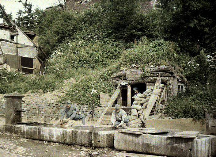PC phone station protected by sandbags. French soldiers doing their laundry in the troughs of a fountain. France, 1917