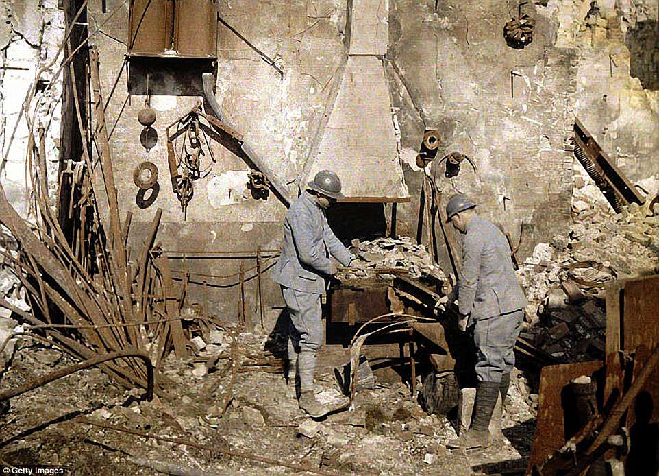 Two French soldiers working at the smith's hearth in a forge destroyed by grenades, in Reims, France, 1917