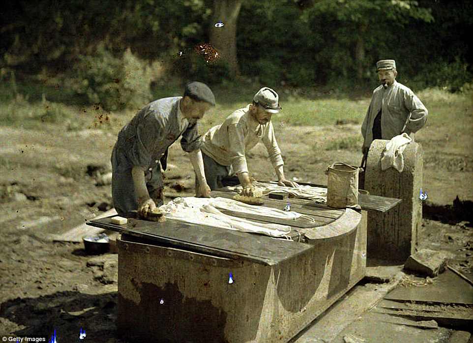 Three French soldiers do their laundry at a well in Soissons, 1917