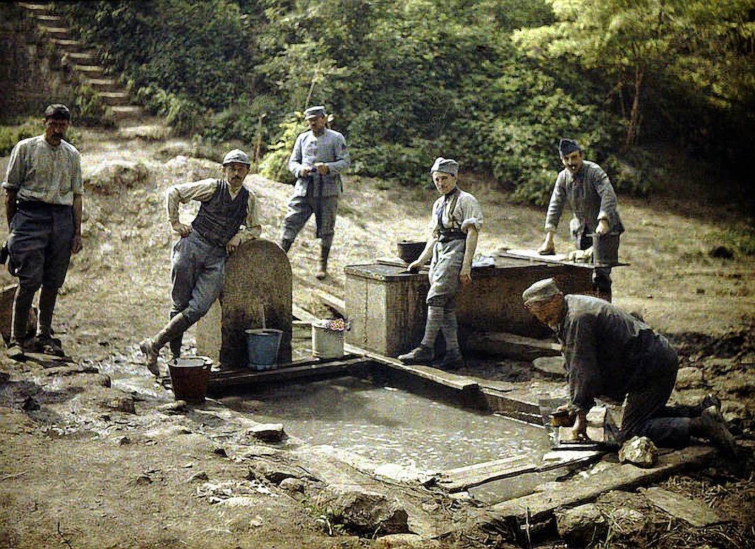 Six French soldiers with buckets and laundry at a fountain, 1917.