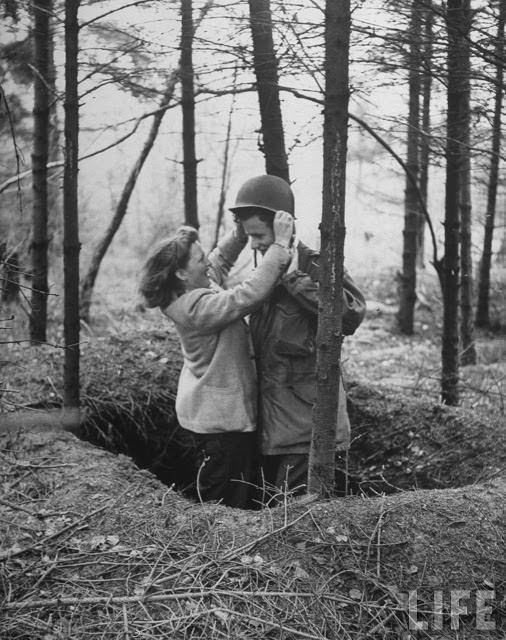 Ernie Kreiling gets helmet put on his head by his laughing wife in the foxhole where he first heard an enemy shell during their vacation tour of battlefields were he fought during WWII in North country.