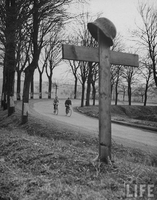 Ernest Kreiling and his bride riding bicycles past German grave.