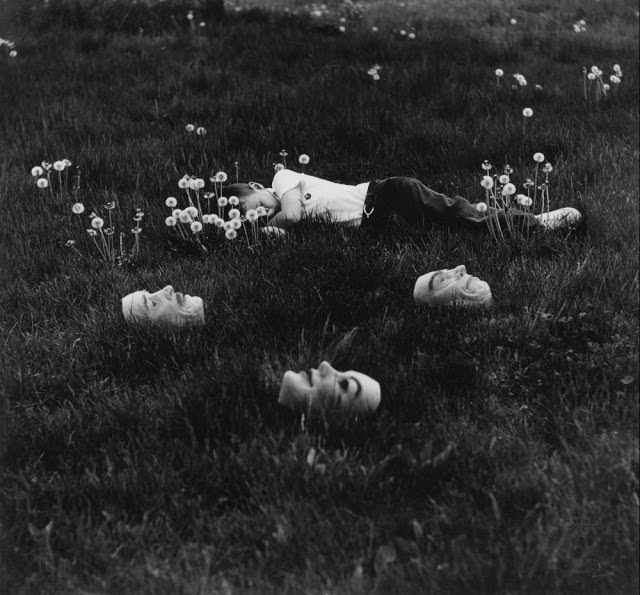 A girl lying in the grass with strange masks