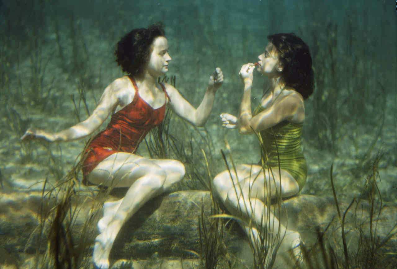 Two swimmers applying lipstick underwater, 1944
