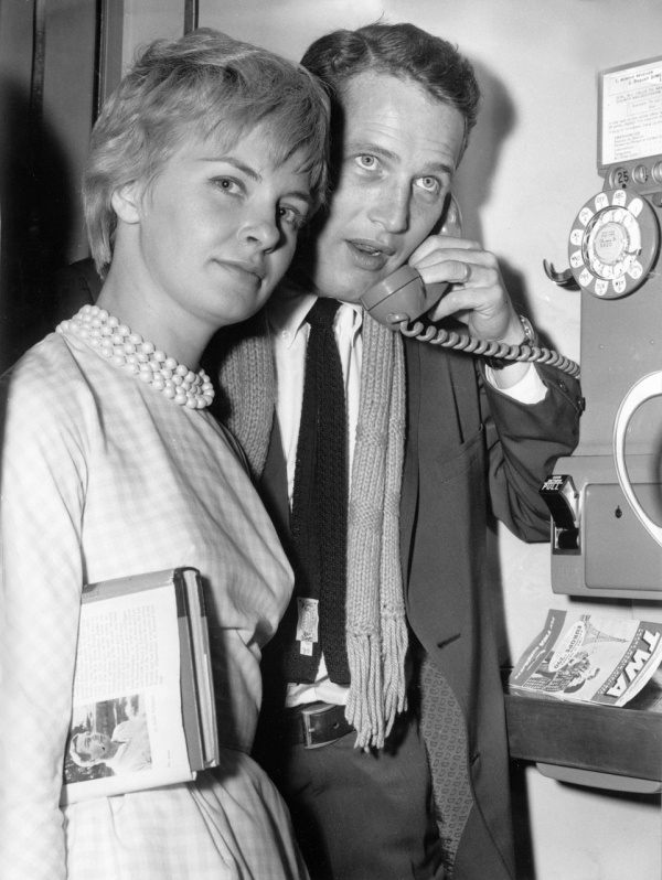 Paul Newman on the phone standing with Joanne Woodward, 1960