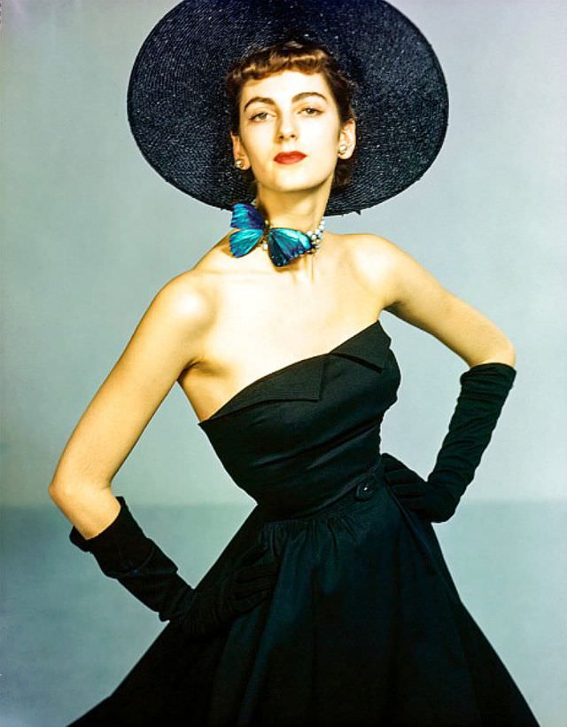 Carmen Dell' Orefice in strapless black piqué dress with full skirt, wide-brimmed hat and butterfly necklace, 1949.