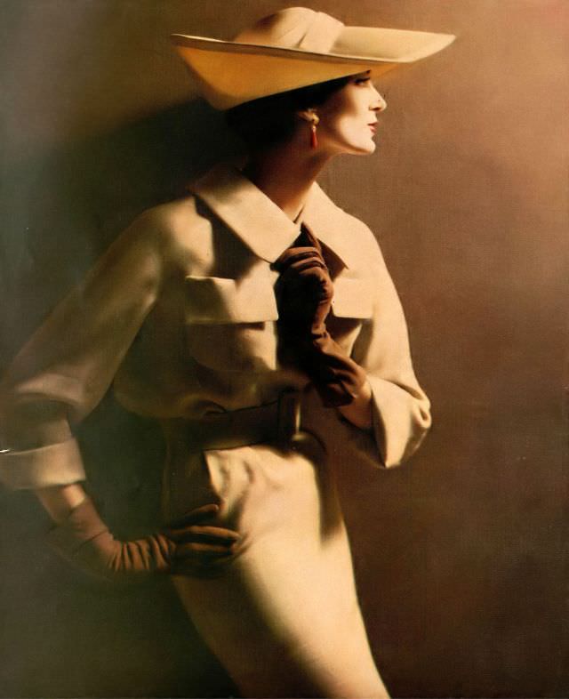 Carmen Dell' Orefice in beige wool and silk suit with patch pockets set high on the bosom worn with thin straw hat, 1958.