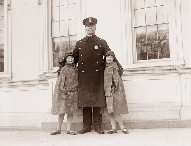 Twin girls posing with a police officer