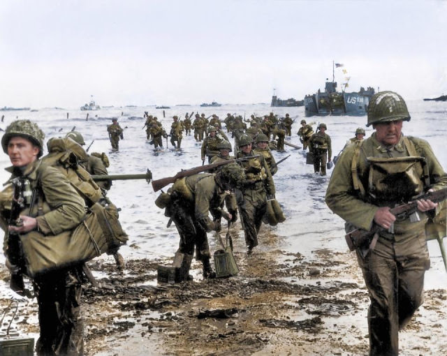 American troops arrive on a Normandy beach in a lengthy procession from their landing crafts.