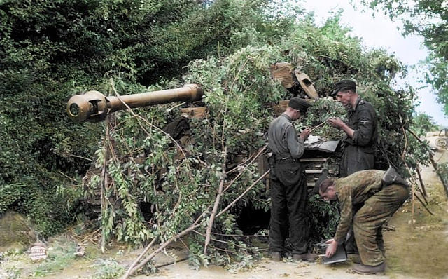 German troops camouflage a Panzer VI Tiger tank with undergrowth in the Normandy village of Villers-Bocage.