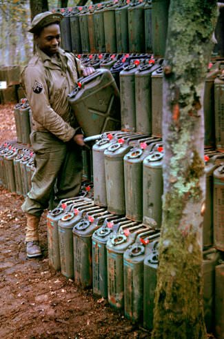 An American corporal stacks cans of gasoline in preparation for the upcoming invasion of France, Stratford-upon-Avon, England.