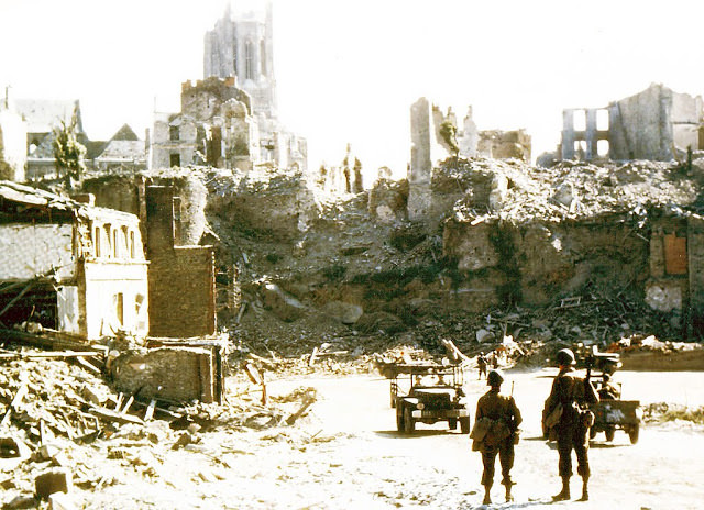Operation Overlord Normandy, Two American soldiers are watching two United States Army jeeps driving through the ruins of the center of Saint-Lo.
