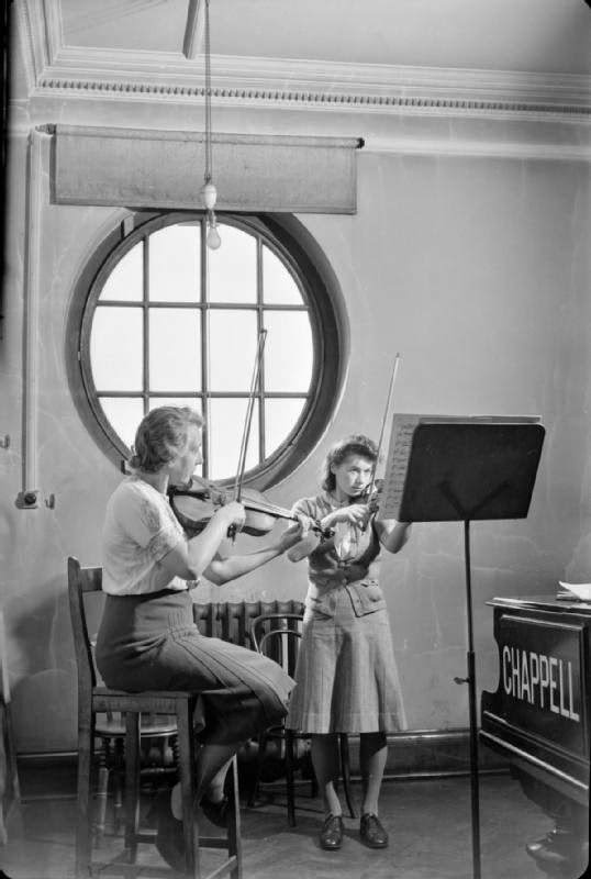 Miss Winifred Small (left) is a BBC soloist and professor at the Royal Academy of Music. Here she can be seen giving a violin lesson to a female first year student at the Academy, 1944.