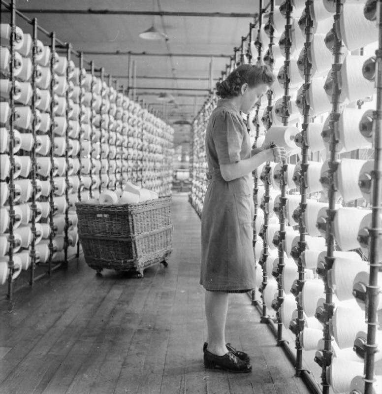 Cotton worker Lilian Alston fits cones of yarn into the V-shaped creel of the warping frame at a cotton mill, somewhere in Lancashire, 1945.