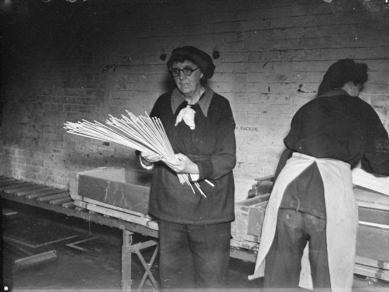 An elderly female munitions worker at the Royal Naval Cordite Factory at Holton Heath counts sticks of cordite before they are packed by her colleague into boxes ready for distribution to various naval armament depots.