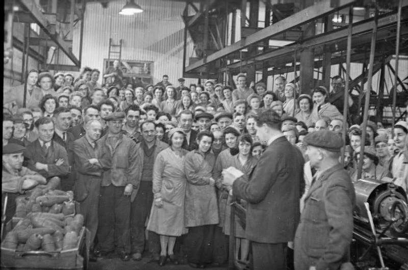 A director, possibly Mr Franklyn Pool, of J & F Pool Ltd reads a telegram from the Ministry of Supply to the workers gathered on the factory floor, congratulating them on the production of their 1 millionth mortar bomb, 1943.