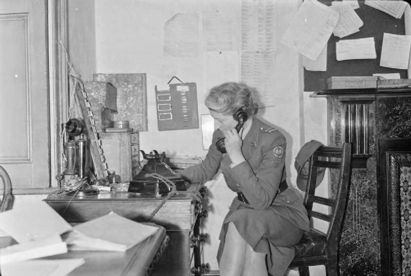 A woman of the American Ambulance Great Britain receives a telephone call requesting their attendance at an incident, 1944.