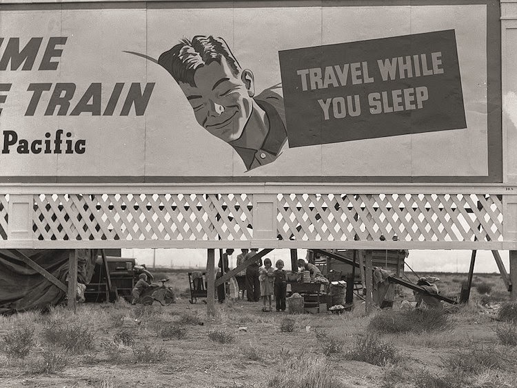 Billboard along U.S. 99 behind which three destitute families of migrants are camped. Kern County, California