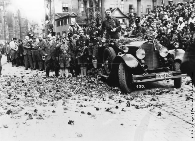 Adolf Hitler drives along a flower strewn road after a rally at Nuremberg, 1929
