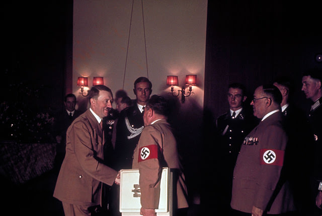 Adolf Hitler shakes hands with one of his personal photographers, Heinrich Hoffmann, while his doctor, Theodor Morrell (right) waits to greet the Fuhrer on Hitler's 50th birthday, April 20, 1939