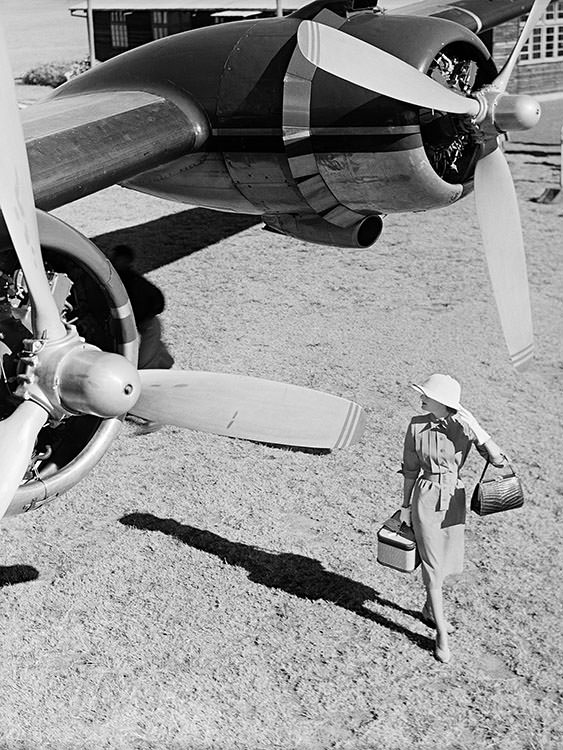 Wenda Parkinson wearing a grey gabardine dress in Nairobi, Kenya, South Africa, next to a Hermes aeroplane, 1951