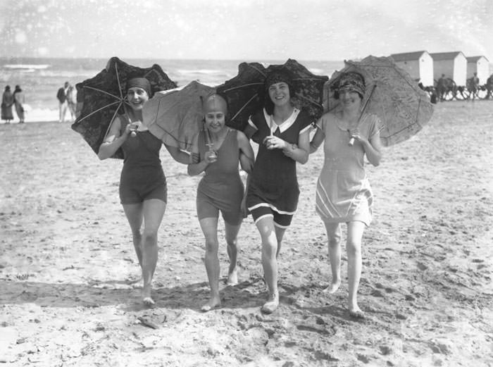 Four bathing belles shading themselves with parasols on the beach at Skegness, 1926