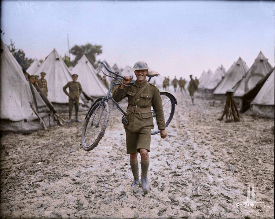 unable to ride his cycle through the mud caused by the recent storm a Canadian messenger carries his horse, August 1917