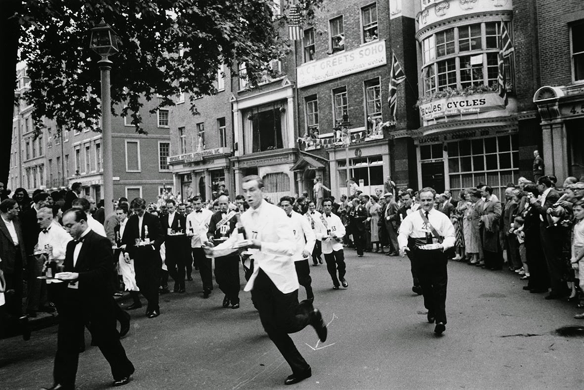 Waiters carrying half bottles of champagne set off on the annual waiters' race from Soho Square to Greek Street, 1955
