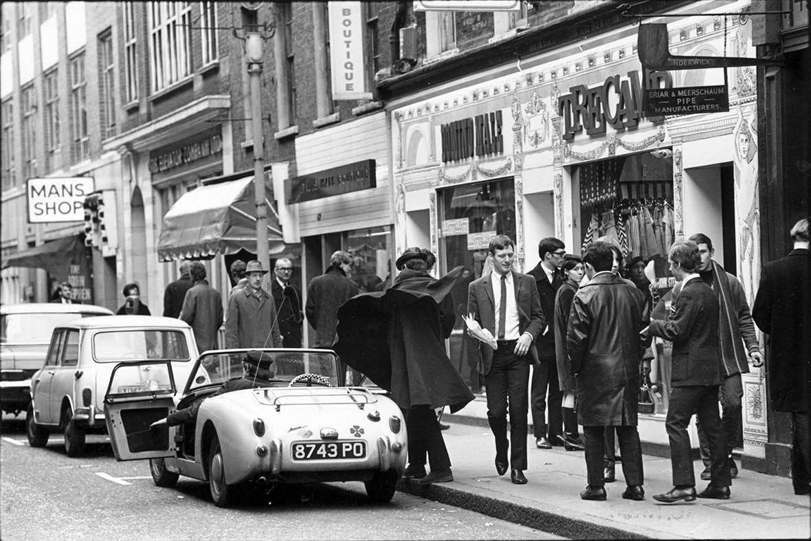 A man sweeps his cloak around him after getting out of a sports car on Carnaby Street, 1966