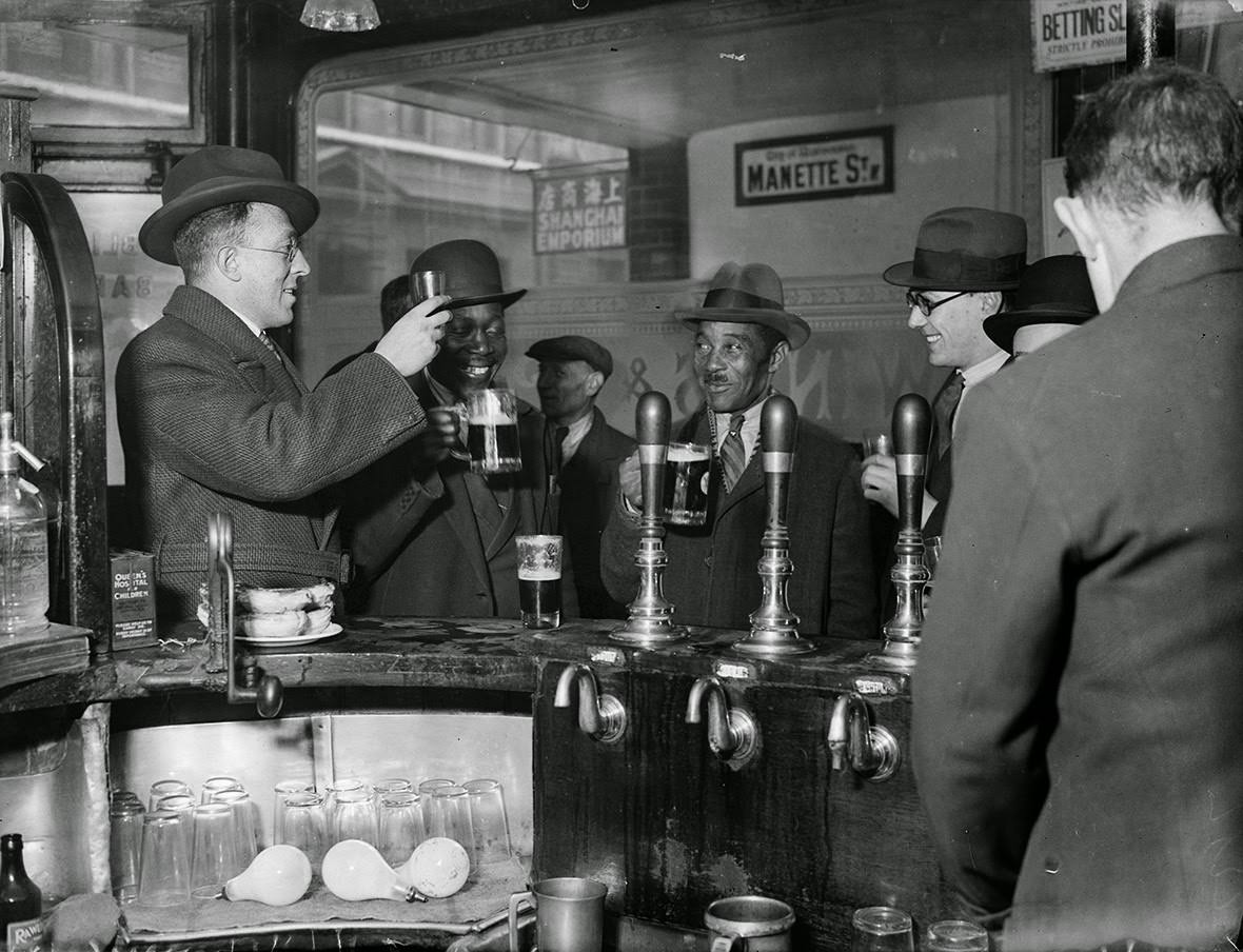 Men raise their glasses in a public house in London's Soho, 1933