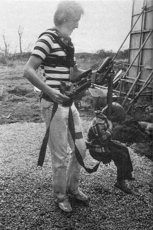 Steadicam inventor Garrett Brown takes actor Danny Lloyd for a ride on his Steadicam just outside the hedge maze set on the backlot at MGM Elstree Studios. Brown discovered that Danny was about the same weight as the camera, so he would often give the boy rides in a makeshift swing hanging from the