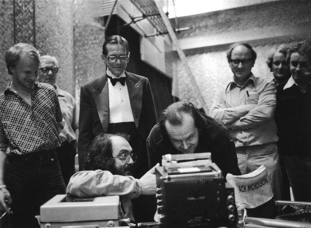 Stanley Kubrick reviews a take with Jack Nicholson on the Gold Room set. Watching from behind are Kubrick assistant Leon Vitali, actor Joe Turkel, Camera Operator Kelvin Pike and Director of Photography John Alcott.